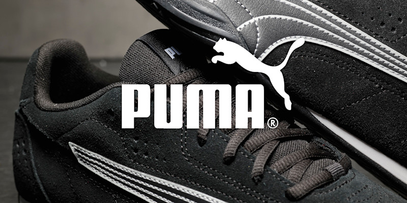 Svarte Puma sportssko med hvite detaljer og logo, i klassisk sporty stil med perforert overflate og snøring. Hvit Puma-logo over bildet.