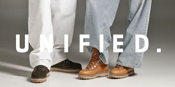 To personer med hvite og blå jeans viser robuste fjellsko i brunt og mørkebrunt lær med kraftige såler. Logoen "UNIFIED." ligger over.