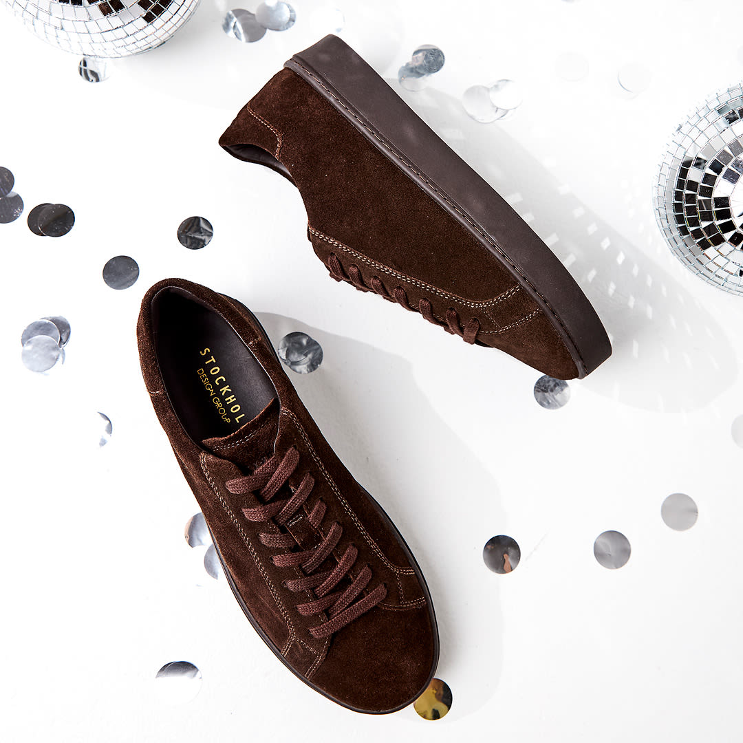 Helbrune semskede skinnsko fra Stockholm Design Group med tykk såle, fotografert på hvit bakgrunn med diskokuler og sølvkonfetti.