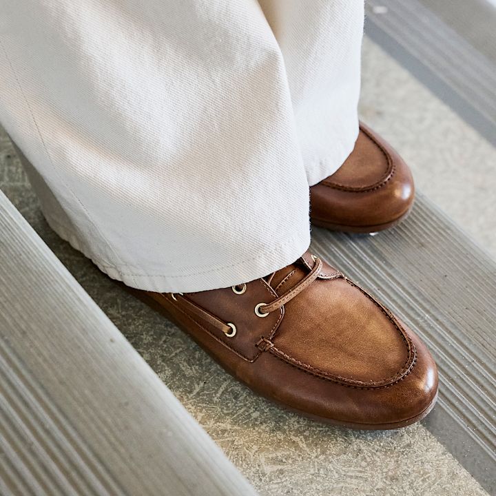 Brune seilersko i skinn med snøring, kombinert med hvite bukser, stående i trapp.