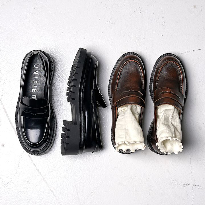 To svarte og to brune chunky penny loafers i lær med tykk såle. De brune har hvite sokker i seg.