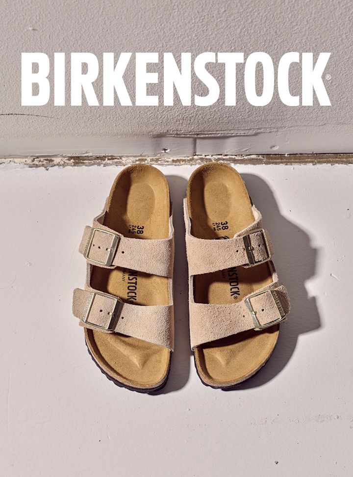 Birkenstock Arizona sandaler i beige semsket skinn med to remmer og spenner, sett ovenfra på hvit flate.